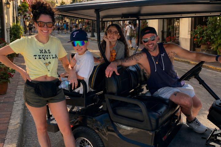 Group posing with a golf cart in a sunny outdoor setting.