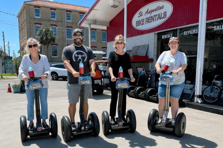 Four people on segways outside St. Augustine Bike Rentals building.