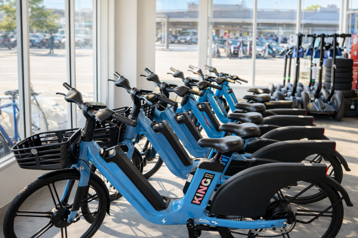 Row of blue rental e-bicycles inside a shop with large windows.