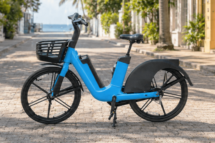 Electric bicycle parked on a sunny cobblestone street.