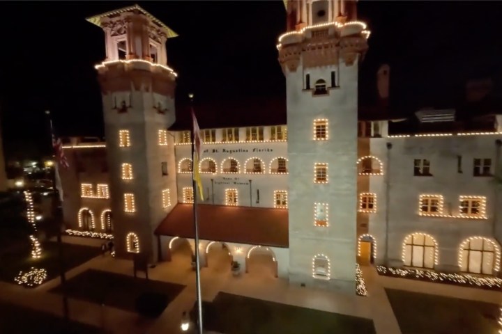 Illuminated historic building with two towers at night.