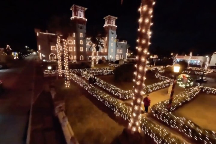 Building and trees decorated with holiday lights at night.
